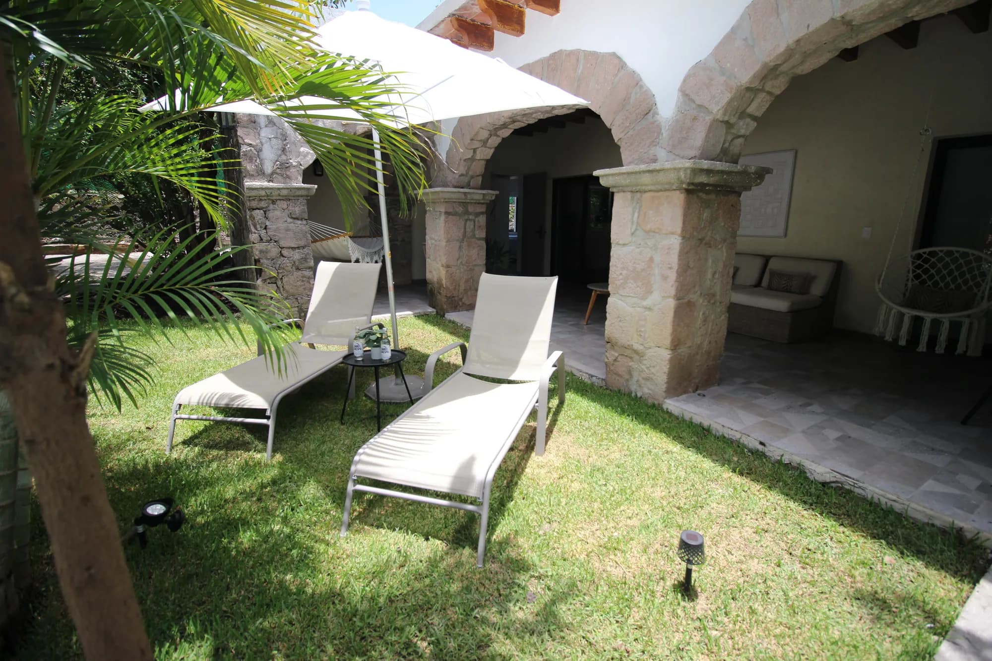 Patio privado con reposeras junto a un arco de piedra en Casa Laureles