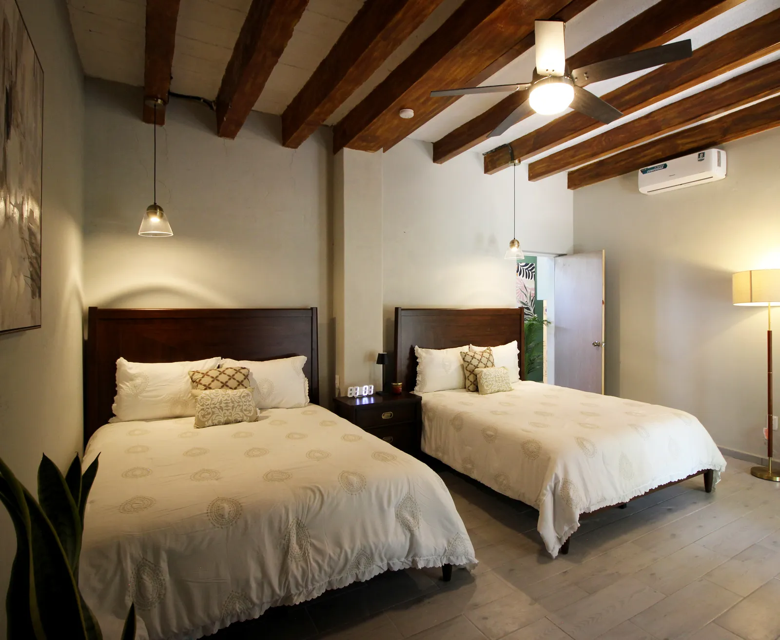Recámara con dos camas matrimoniales y vigas de madera en una suite Casa Laureles